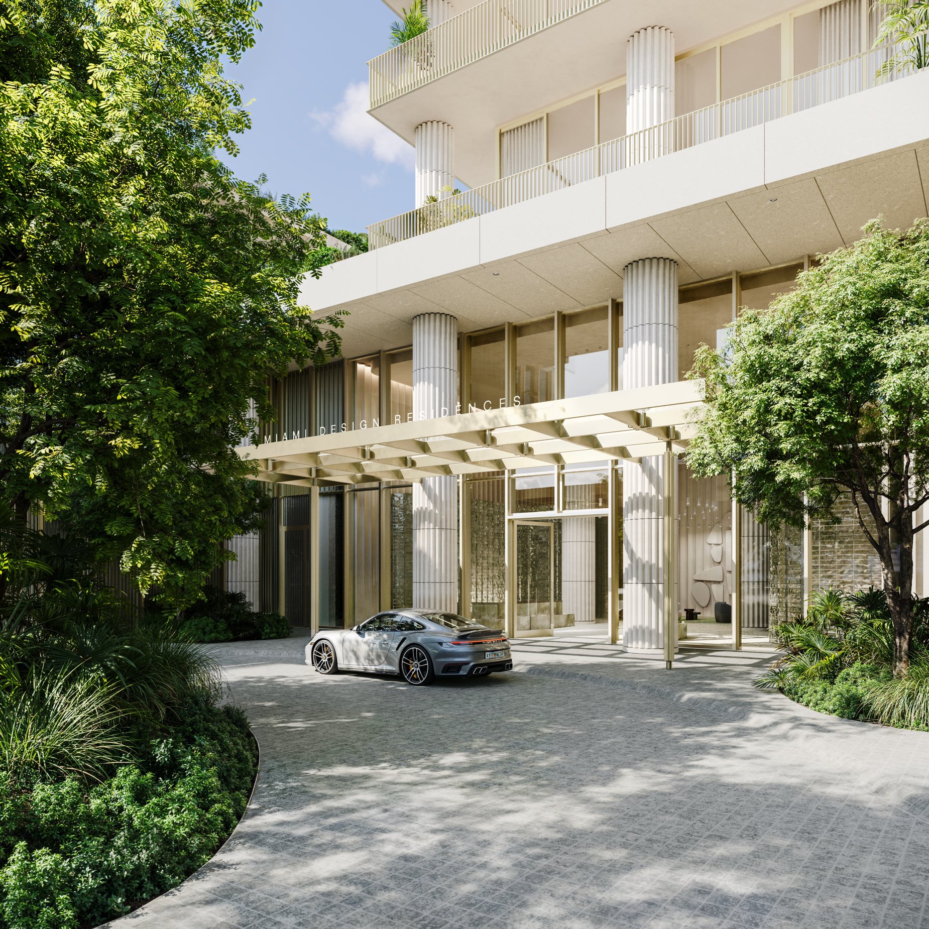 The landscaped motor court and porte-cochère at Fouquet's Hotel & Residences — rounded columns and a cream stone-lattice screen framed by mature trees in the Miami Design District.